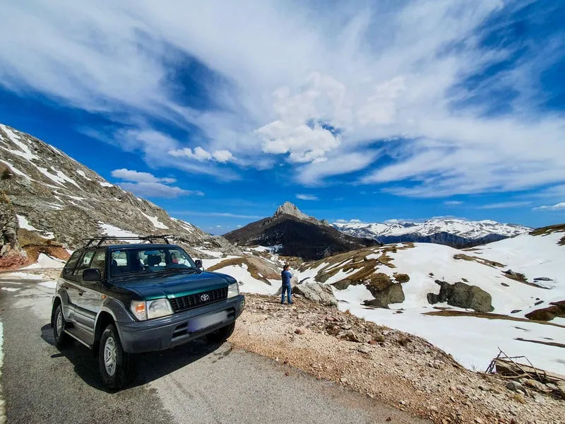 The 4x4 on a mountain track between patches of late snow