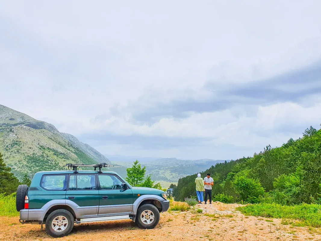 The 4x4 on a dirt road above a wooded valley